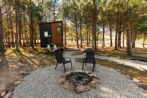 a small cabin with two chairs and a fire pit at Novena Pines by Tiny Away in Thulimbah