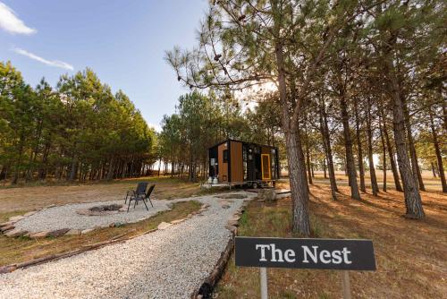 a tiny house in the woods with a sign at Novena Pines by Tiny Away in Thulimbah