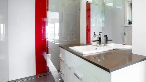 a bathroom with a white sink and a red wall at Three Oaks in Red Hill