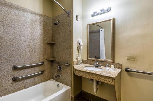 a bathroom with a sink and a tub and a mirror at Comfort Suites Galveston Cruise Port Area - Beachside in Galveston