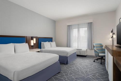 a hotel room with two beds and a chair at Hampton Inn Baltimore Bayview Campus in Baltimore