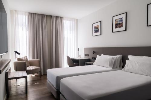 a hotel room with two beds and a desk at Hotel Ogar Tomelloso in Tomelloso