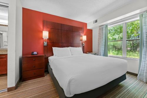 a bedroom with a large bed with an orange wall at MainStay Suites Appleton Airport - Fox River Mall Area in Appleton