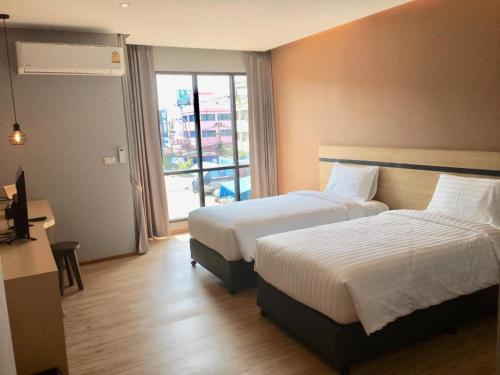 a hotel room with two beds and a window at Sans Hotel in Ban Rong Chang