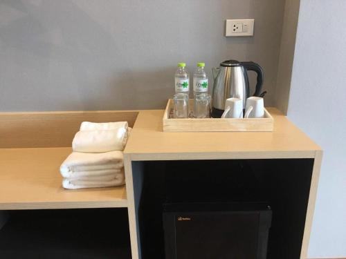 a counter with bottles and a coffee pot and towels at Sans Hotel in Ban Rong Chang
