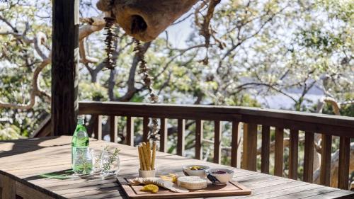 a wooden table with a tray of food on a deck at Coastal Wilderness Retreat in Hardys Bay