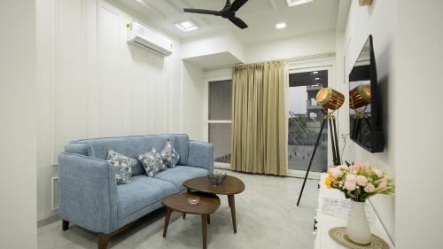 a living room with a blue couch and a table at The Afternoon Stays in Mohali