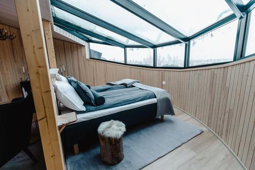 a bed in the middle of a room with windows at Livo Arctic Resort in Posio