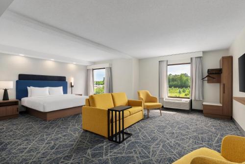 a hotel room with a bed and yellow chairs at Hampton Inn Farmville in Farmville