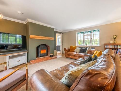 a living room with a leather couch and a fireplace at Scarrow Beck House in Hanworth