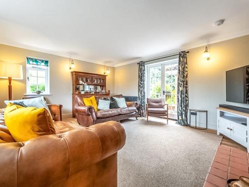 a living room with a leather couch and a television at Scarrow Beck House in Hanworth