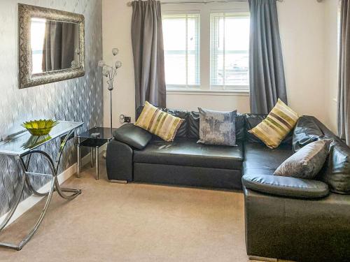 a living room with a black leather couch and a table at Serenity in Cellardyke