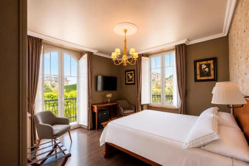 a bedroom with a bed and a chair and windows at Casona Naviega in Navia