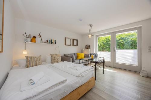a white bedroom with a large bed and a table at Stabenweg Whg. 1 in Göhren
