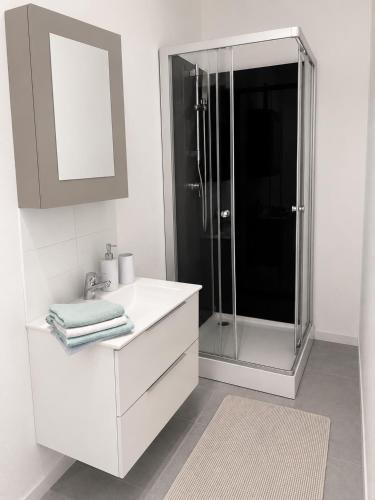 a white bathroom with a shower and a sink at Violette 2 in La Souterraine