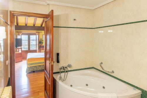 a bath tub in a room with a bedroom at Hotel Rey Don Jaime in Morella