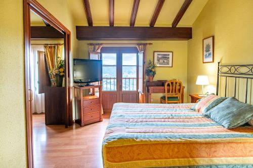 a bedroom with a large bed and a television at Hotel Rey Don Jaime in Morella