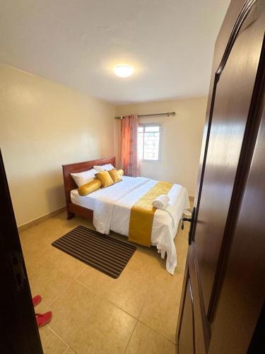 a bedroom with a large bed with yellow pillows at MakerereViewAirbnb in Kampala