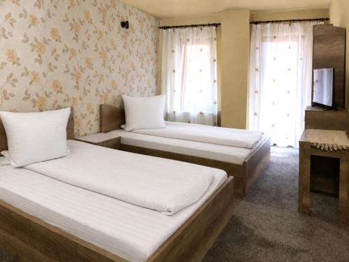 two beds in a room with two windows at Pensiunea Mirela Bears Cave in Chişcău