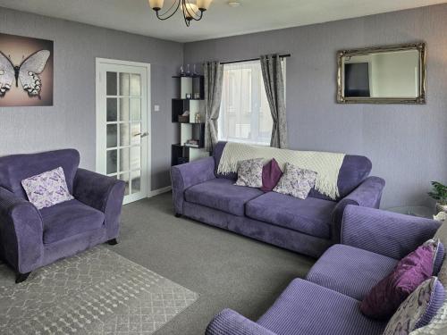 a living room with a purple couch and two chairs at Mo Dhachaidh in Gairloch