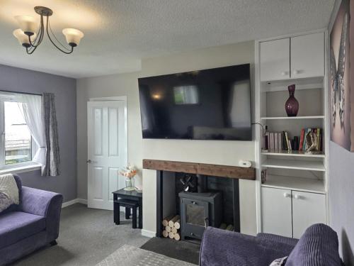 a living room with a fireplace and a tv at Mo Dhachaidh in Gairloch