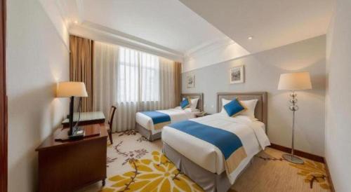 a hotel room with two beds and a desk at Datong Hotel in Datong