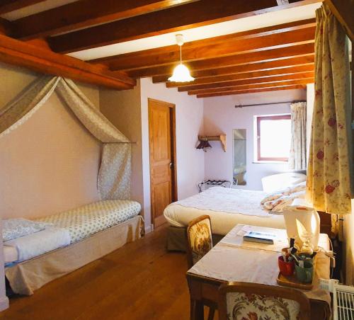 a bedroom with two beds and a table and a table sidx sidx sidx at Logis Hôtel Auberge de la Hulotte in Saint-Jacques-dʼAmbur