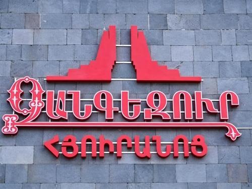 a red neon sign on a brick wall at Zangezur Hotel in Goris
