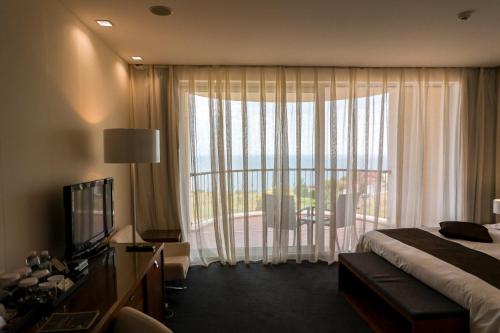 a hotel room with a bed and a large window at Lighthouse Golf & Spa Hotel - Mineral Pools, Premium All Inclusive, SPA & Beach Access, Free Parking in Balchik