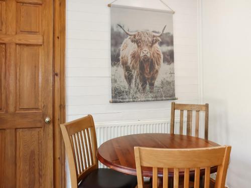 a dining room with a table and a picture of a bull at Weaver's Cottage in Banchory