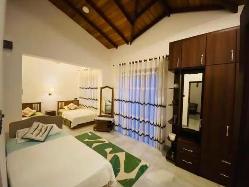 a bedroom with two beds and a large window at Villa Mistora in Kandy