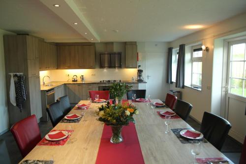 une salle à manger avec une grande table et des chaises rouges dans l'établissement Duinoord Oostkapelle, à Oostkapelle