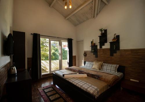 a bedroom with a bed and a large window at The Chill Inn ''Families Only'' By Green Leaves in Ooty