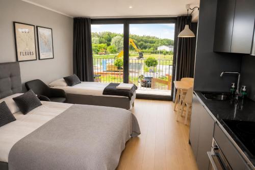 a room with two beds and a kitchen with a balcony at HOOM Home & Hotel Järfälla in Järfälla