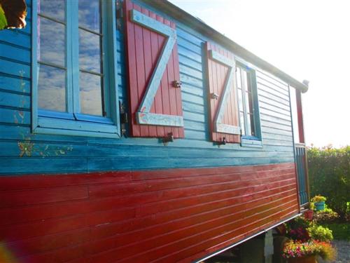a blue and red house with windows and flowers at La Petite Fadette in Sancoins