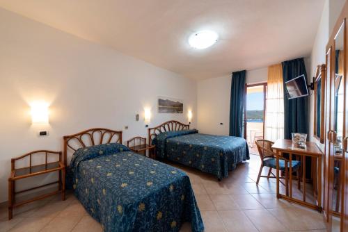 a hotel room with two beds and a table at Albergo Le Briciole in Marciana Marina