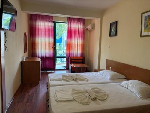 a hotel room with a bed with white sheets and bows at Tanya Hotel in Sunny Beach