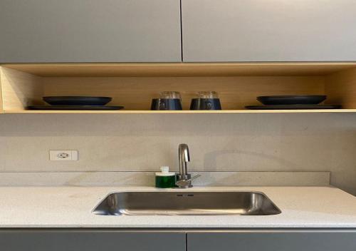 a kitchen counter with a sink and bowls on a shelf at Premium Taman Anggrek Residences in Jakarta