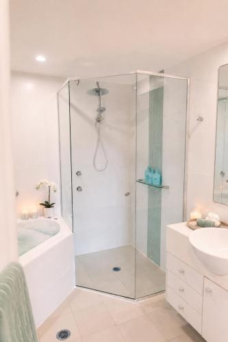 a white bathroom with a shower and a sink at Newly Restyled Resort 2 Bedroom Unit Oaks Pacific Blue in Salamander Bay