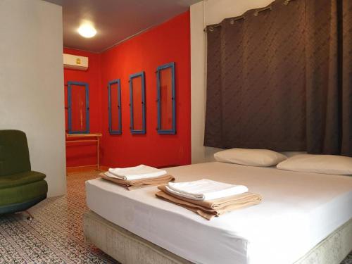 a bedroom with a bed with red walls and a chair at Super Hostel in Nonthaburi