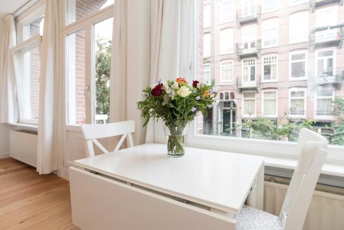 a vase of flowers on a white table in front of a window at Old / New Pijp in Amsterdam