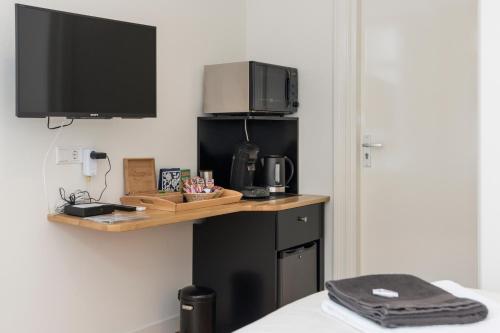 a room with a desk with a microwave and a television at Old / New Pijp in Amsterdam