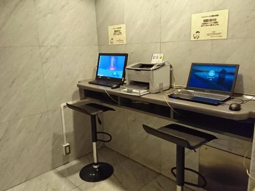 two laptops on a counter with a printer and two stools at Hotel Oaks Early-Bird Osaka Morinomiya/ Vacation STAY 28682 in Osaka