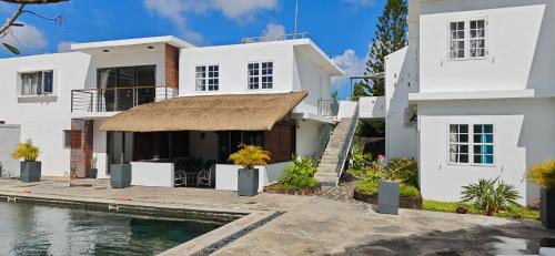 a white house with a swimming pool in front of it at Résidences Le Beau Manguier in Pereybere