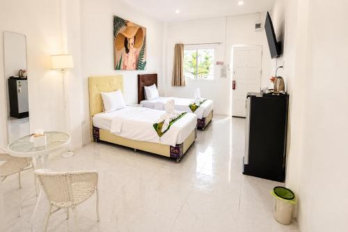 a hotel room with two beds and a table at White House Hotel Kamphaeng Phet in Ban Tha Dua
