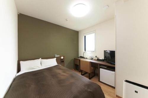a bedroom with a bed and a desk and a television at Hotel Sun Clover Koshigaya Station - Vacation STAY 55366 in Koshigaya