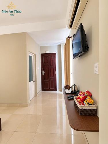 a living room with a table and a tv on a wall at Mộc An Thảo Hotel in Quy Nhon