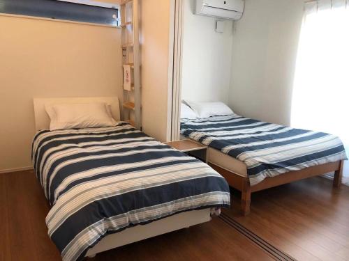 two beds in a small room with a mirror at Methodnet Hanazono B / Vacation STAY 77522 in Chiba