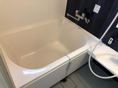 a white bath tub in a bathroom with a toilet at Methodnet Hanazono B / Vacation STAY 77522 in Chiba