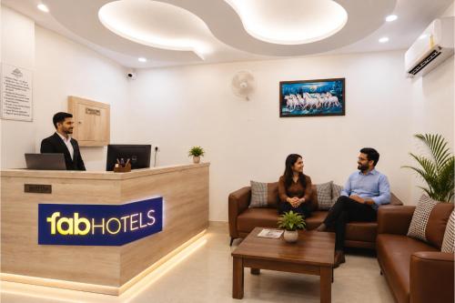 three people sitting at the reception desk of a hotel lobby at FabHotel K9 Regency in Zirakpur